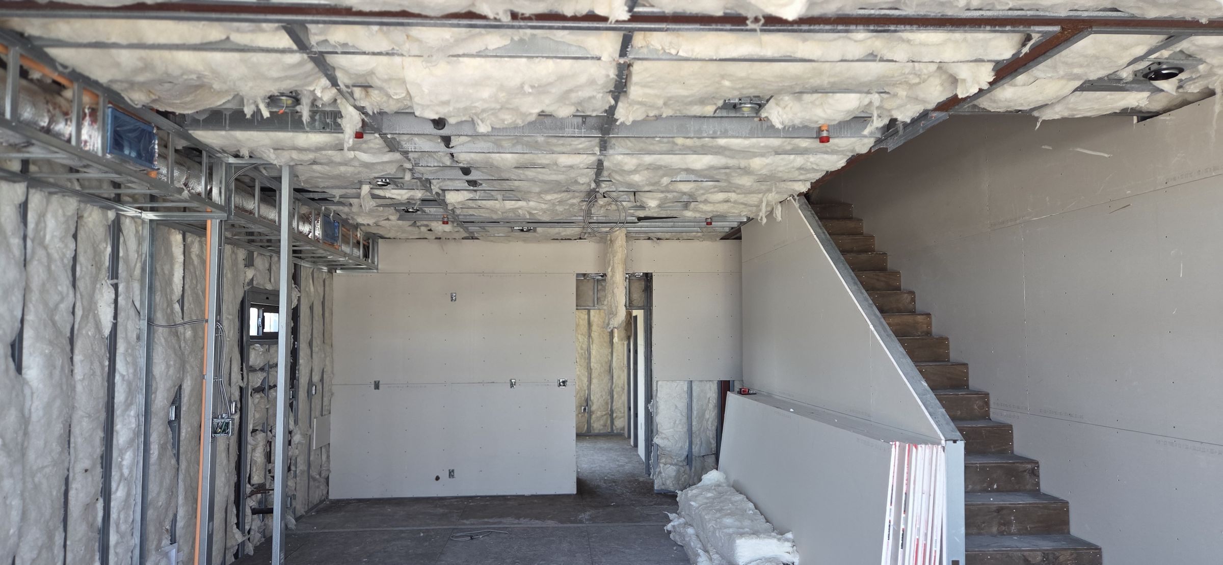 Drywall hung and taped around a new stairwell on a San Diego commercial buildout