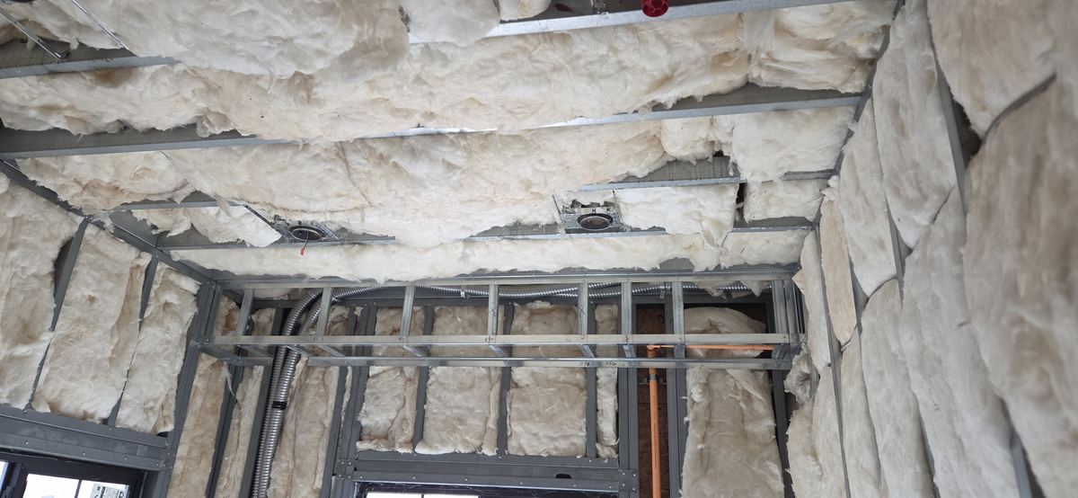 Ceiling framing and insulation coordinated overhead.